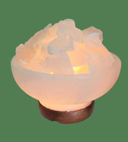 A White Himalayan Salt Firebowl with pure salt chunks, glowing with a soft pink light, set on a rosewood base with an electric cord.