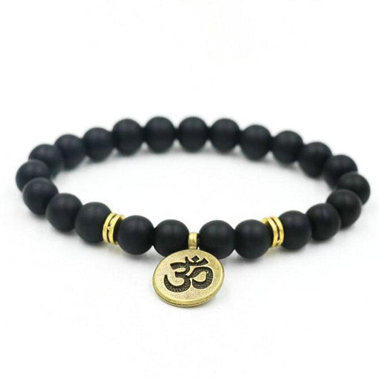 Black beaded bracelet with a gold Om symbol charm on a white background