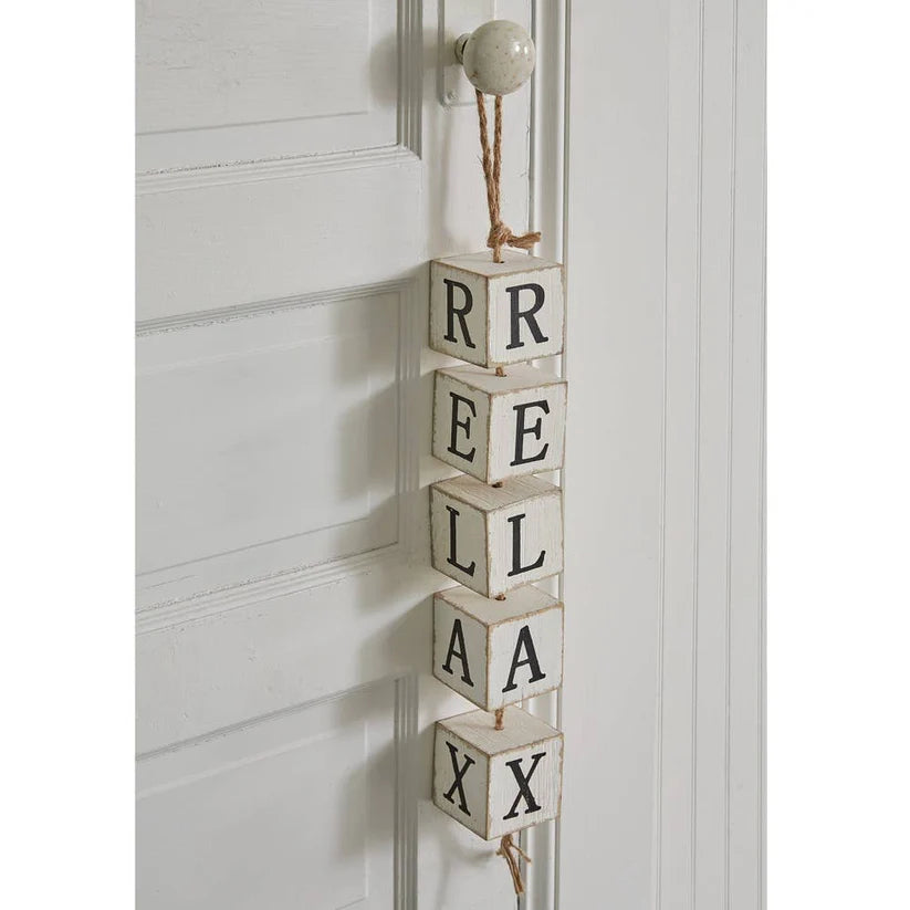 Decorative wall hanging with wooden blocks spelling 'REEL RELAX' on a white door.