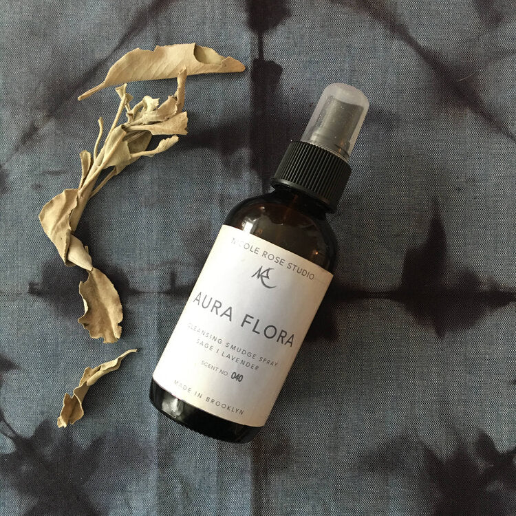 Sage Cleansing Smudge Spray on a textured gray surface with dried leaves.
