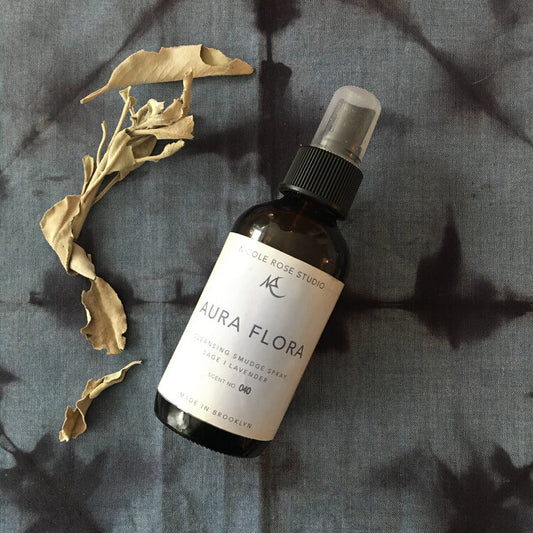 Sage Cleansing Smudge Spray on a textured gray surface with dried leaves.