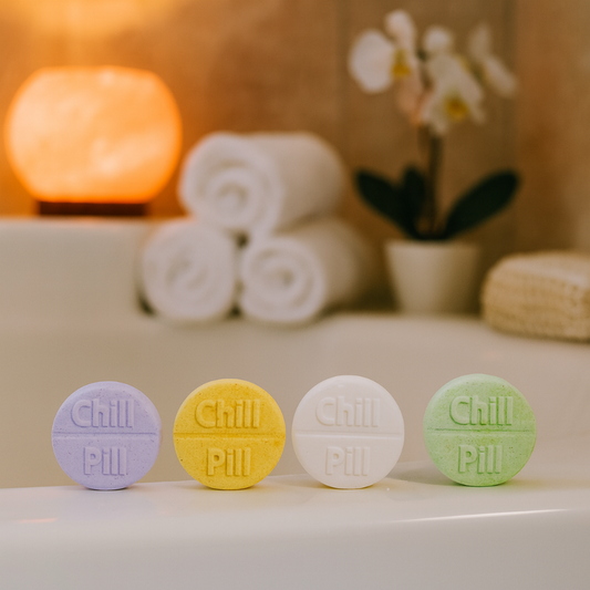 Four 'Chill Pill' tablets on a surface with towels and a plant in the background.