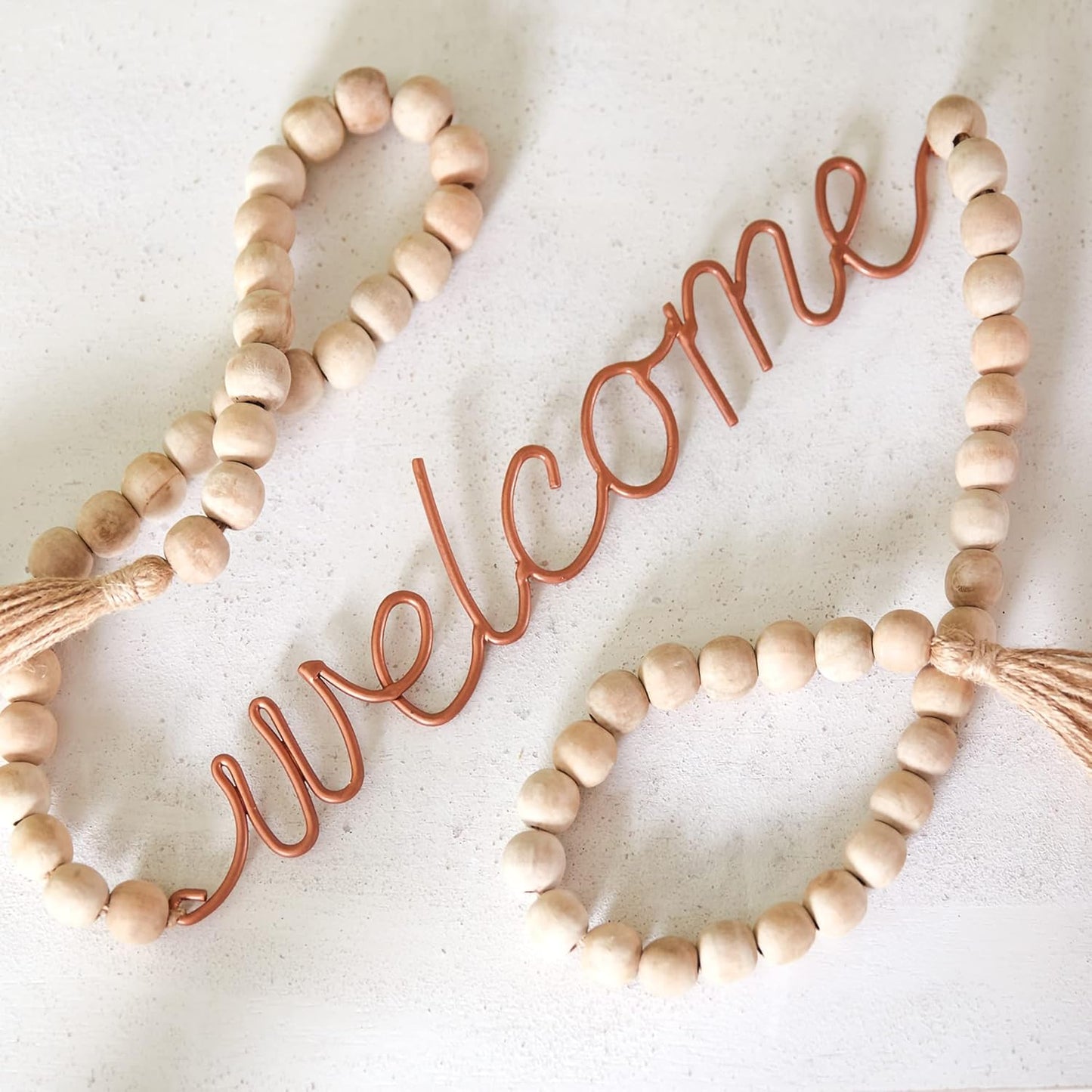 Decorative 'welcome' sign with wooden beads on a white background