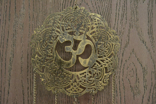 Decorative brass pendant with Om symbol on a wooden background